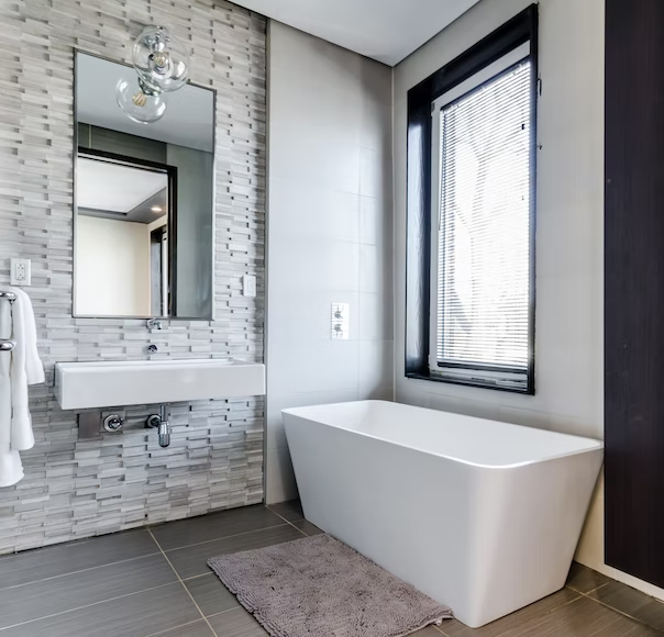 large soaking tub with vessel sink and brick wall textured bathroom wall 